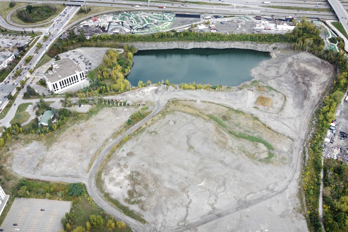 航拍：高速公路旁一大片空地和一个积水的旧采石坑，是 Carré Laval 预定地