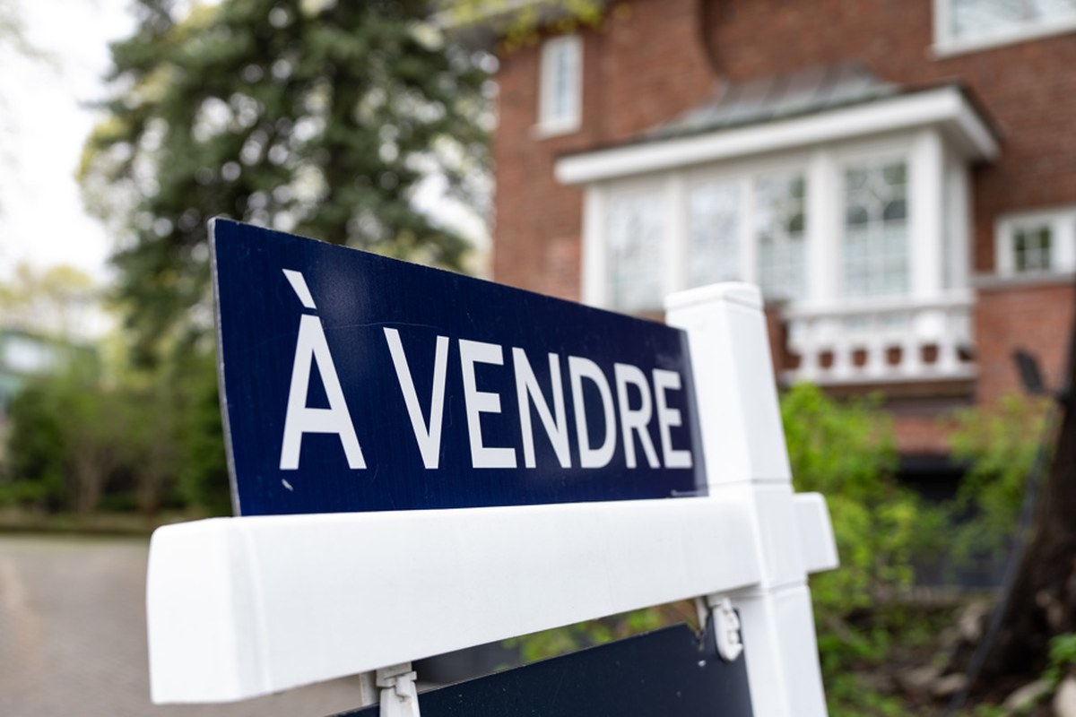红砖房前立着一块写着「À VENDRE」（出售）的法文牌子